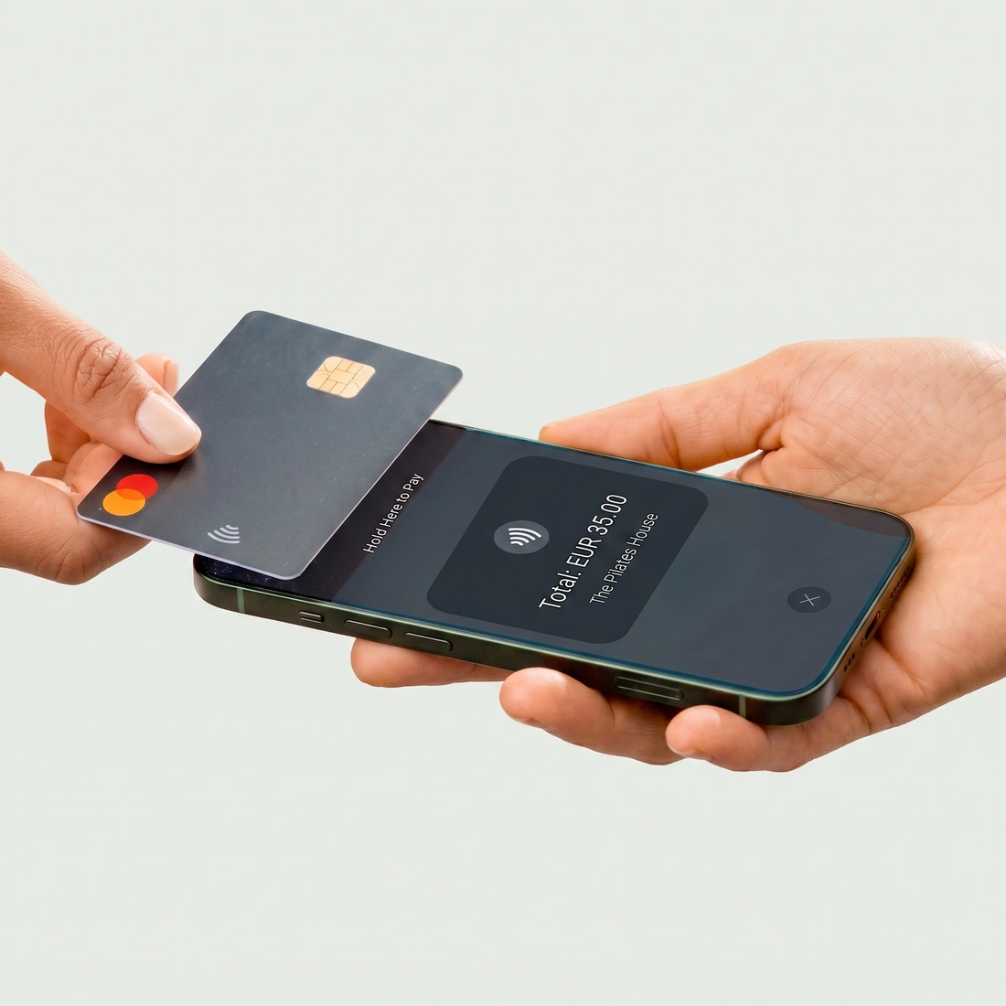 A customer holding their card against the studio’s phone with Tap to Pay, with the total on the screen.
